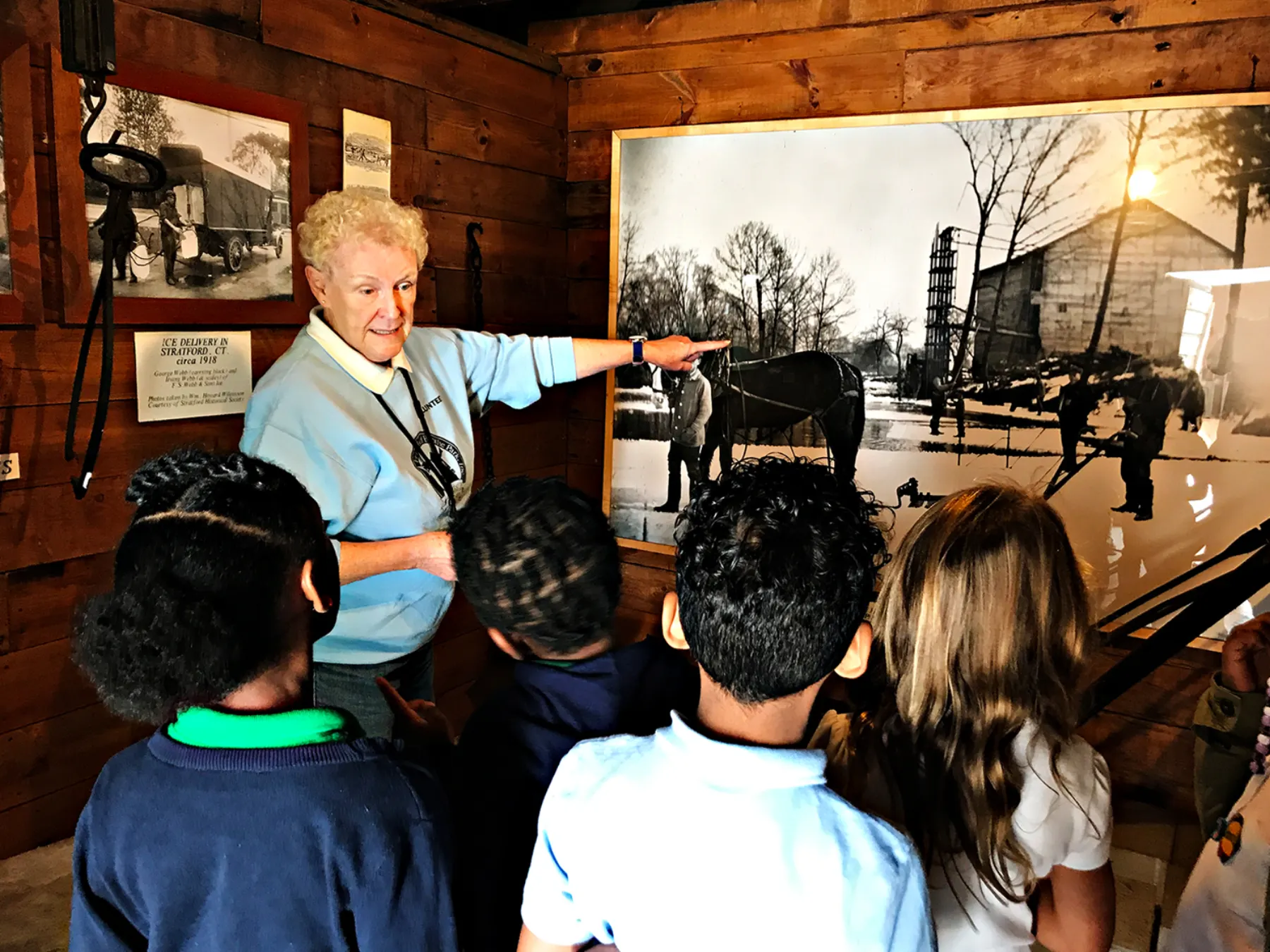 A volunteer leading children through a Boothe Park museum exhibit